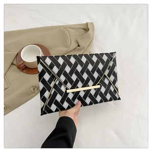 Détail de la pochette enveloppe tissée noire et blanche avec bordure dorée et fermoir
