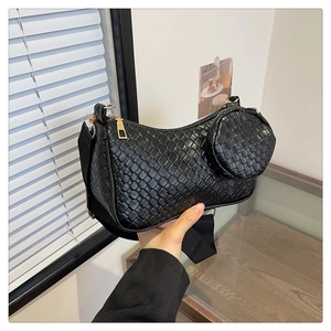 Détail du sac baguette noir tissé avec ferrures dorées et petite pochette ronde