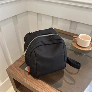 Lightweight black nylon canvas shell bag with gold zippers and orange tag for daily casual use