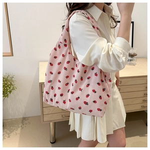 Detail of pink corduroy tote bag with strawberry print and soft textured fabric surface