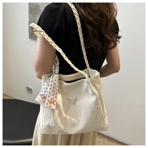 Detail van witte tote bag met crinkle-textuur, zijden sjaal en geweven schouderriem