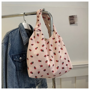 Detail of pink corduroy tote bag with strawberry prints hanging on a stainless hanger