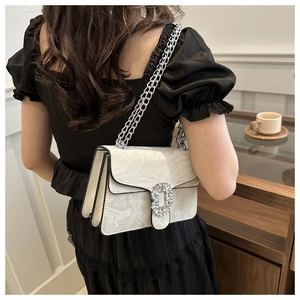 Detail of white marble textured shoulder bag with rhinestone buckle and chain straps