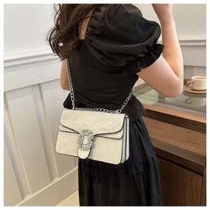 Detail view of white marble patterned crossbody bag with a large rhinestone buckle and chain