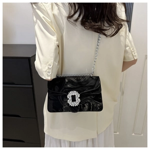 Detail of glossy black patent leather bag with silver rhinestone-encrusted buckle