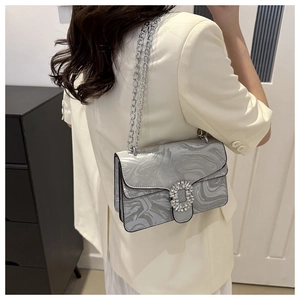 Close-up of marble texture shoulder bag with crystal buckle and silver chain on model