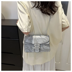 Detail showing marble texture shoulder bag with rhinestone buckle worn by a model