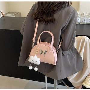 Pink bowling handbag with metal butterfly and cloud charm worn on shoulder