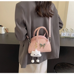 Detail of pink bowling bag featuring silver butterfly and plush cloud charm strap