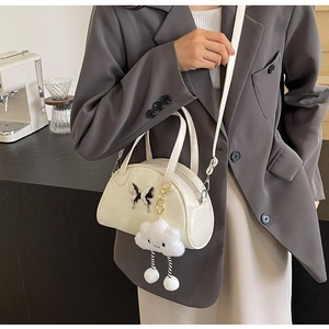 Detail of white bowling bag with black butterfly clasp and plush cloud charm accessory