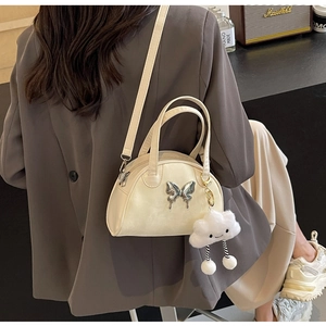 Detail of cream leather bowling bag with silver butterfly charm and fluffy cloud pendant