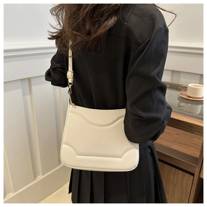 Dettaglio di una borsa a tracolla crema con eleganti texture in rilievo aerodinamiche