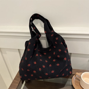 Sac cabas en velours noir avec imprimé fraises posé sur une table en bois au café