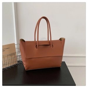 Detailed view of the caramel PU leather tote bag with unique flap handle design