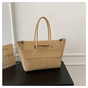 Close-up of beige tote bag featuring a unique folding flap design and sturdy handle