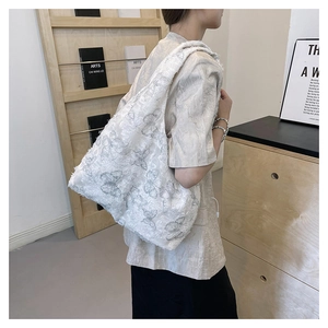 Detail of white embroidered tote bag featuring grey butterfly patterns and frayed edges