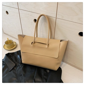 Close-up of structured beige tote bag with unique handle through flap design