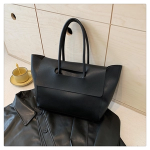 Close-up of a large black leather tote bag featuring a unique flap handle design
