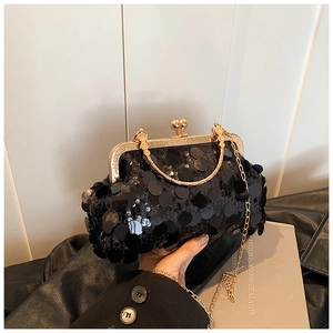 Détail d'un sac de soirée à paillettes noires avec cadre doré et bandoulière chaîne
