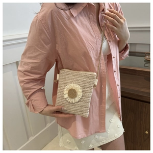 Detail of beige straw crossbody bag with 3D sunflower decor worn on shoulder