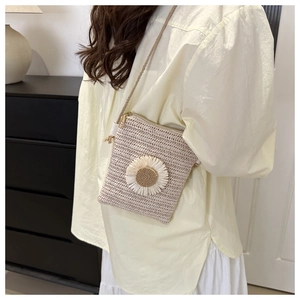 Detail of woven straw crossbody bag with daisy floral accent worn by a person