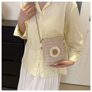 Close-up of hand-woven straw crossbody bag featuring a white daisy flower applique