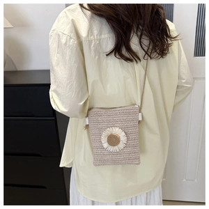 Detailed view of handmade woven straw crossbody bag featuring a white 3D daisy flower