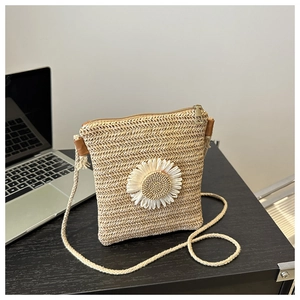 Detail of hand-woven straw crossbody bag with 3D white daisy floral decoration
