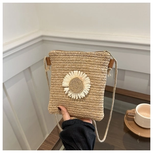Macro detail of hand-woven straw crossbody bag with white daisy flower and metal zipper