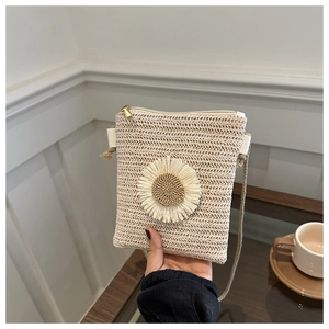 Detail of a beige woven mini bag featuring a large white sunflower and gold zipper closure