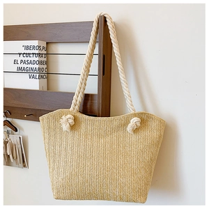Detail of hand-woven beige straw tote bag with chunky white cotton rope knotted handles