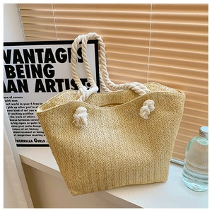 Detail of woven straw tote bag with white cotton rope handle and rustic metal eyelets