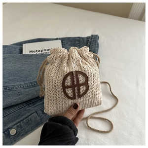 Détail du sac seau tissé beige avec logo en cuir marron et fermeture à cordon de serrage