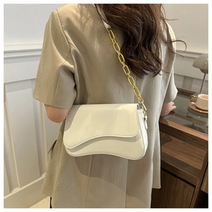 Close-up of stylish white crossbody bag with premium gold chunky chain shoulder strap