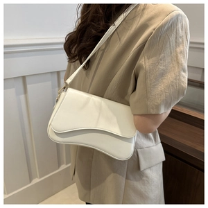 On-body view of white minimalist shoulder bag with irregular flap and gold hardware