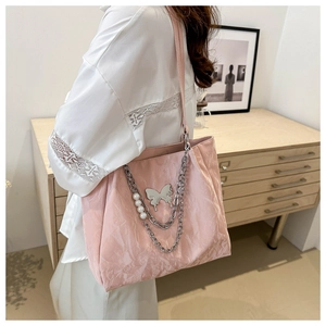 Dettaglio borsa tote rosa con trama a pieghe catena di perle e ciondolo a farfalla