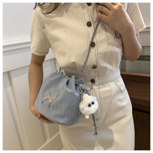 Detail of light blue bucket bag with silver butterfly charm and chain shoulder strap