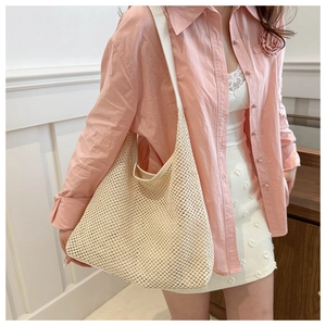 Détail du sac hobo en maille beige montrant le motif de tricot ajouré sur l'épaule
