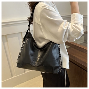 Detail of black leather bucket bag featuring chain strap and MUDOU COLO embossed logo