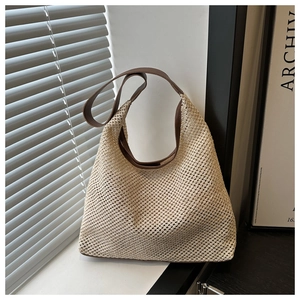 Détail du sac cabas en maille tressée avec anses en cuir marron et texture filet