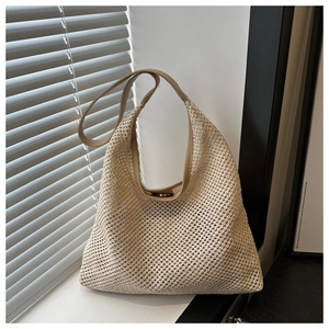 Détail du sac de plage tressé beige avec texture en maille et anses en cuir lisse