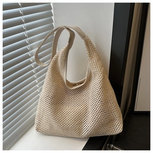 Détail de la texture en maille évidée tissée main sur un sac cabas en paille beige