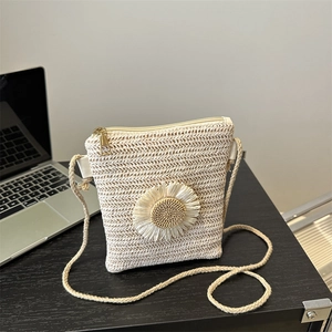 Minimalist straw crossbody bag with large sunflower decoration on black background