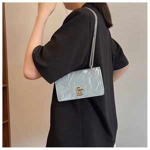 Side view of woman wearing a crinkled silver chain bag with a black suit jacket