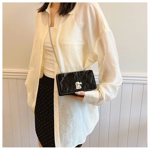 Detail of black wrinkled texture crossbody bag with silver clasp and chain strap