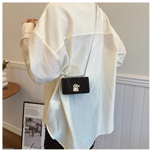 Close-up of black textured crossbody bag with silver chain and keyhole lock detail