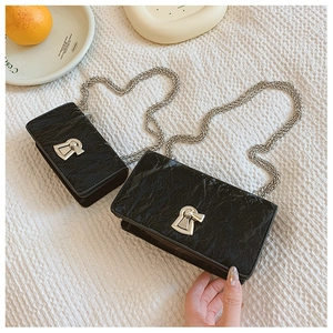Detail view of black pleated crossbody bags with silver chain straps and metallic locks