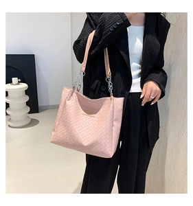 Detail of pink woven tote bag featuring silver chain strap and leather handle