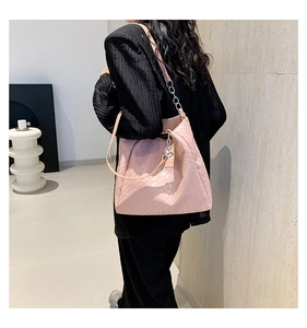 Detailed view of pink woven leather tote bag with metallic chain strap on shoulder