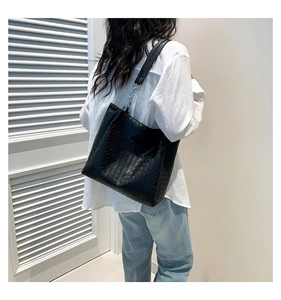 Close-up of black woven leather tote bag with Intrecciato pattern and Fashion label
